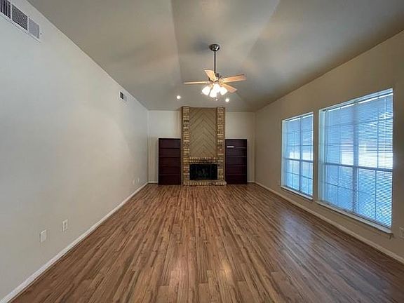 Unfurnished living room with ceiling fan, dark wood-style flooring, a fireplace, and lofted ceiling