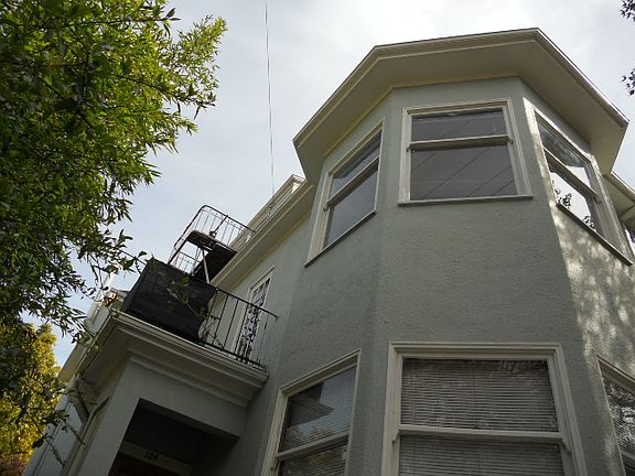 Living room bay windows and deck viewed from street level.