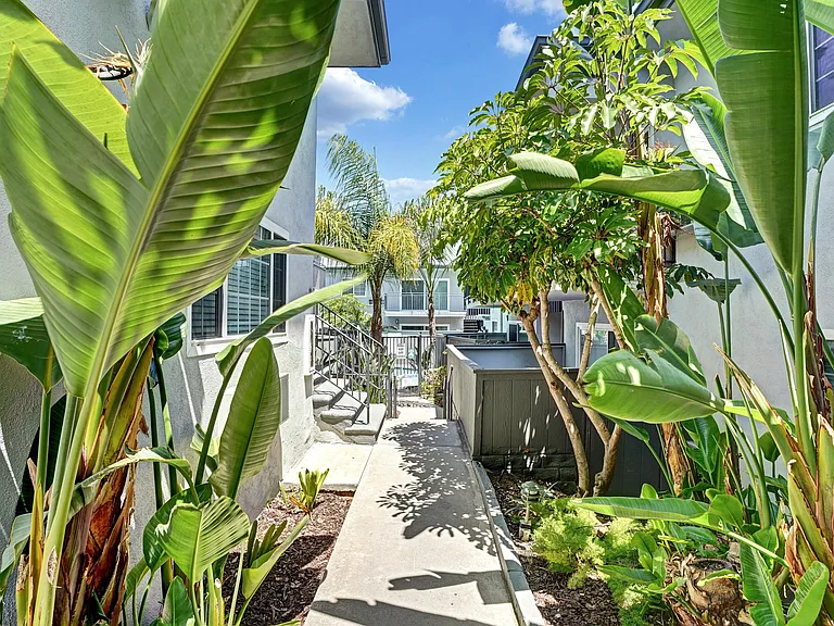 A small garden with a concrete pathway and a metal railing.