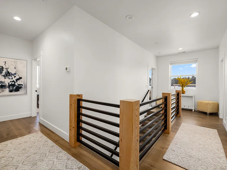 Bright and inviting second-floor hallway, offering access to the primary suite, bonus room, additional bedrooms, and dedicated laundry room, all tied together with warm mountain-modern finishes.