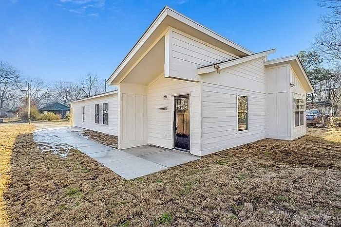 A sleek, modern bungalow featuring a white board-and-batten facade, asymmetrical roofline, and clean concrete driveway.
