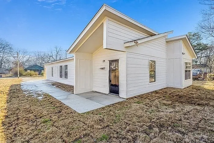 A sleek, modern bungalow featuring a white board-and-batten facade, asymmetrical roofline, and clean concrete driveway.