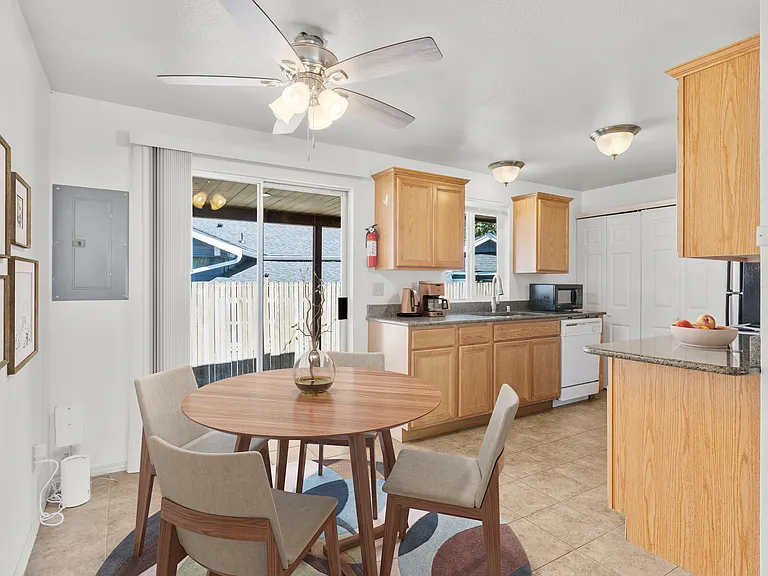 Staged dining area with ceiling fan opens to kitchen. Slider to backyard patio and fenced backyard