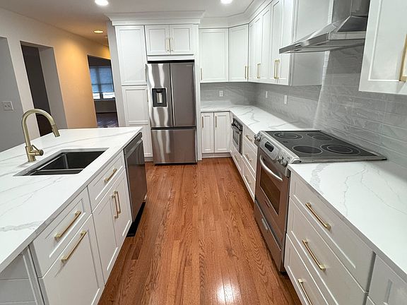 New renovated kitchen with new custom cabinets with custom crown molding, new tile backsplash, new quartz countertops, all new fixtures and new wood floor.