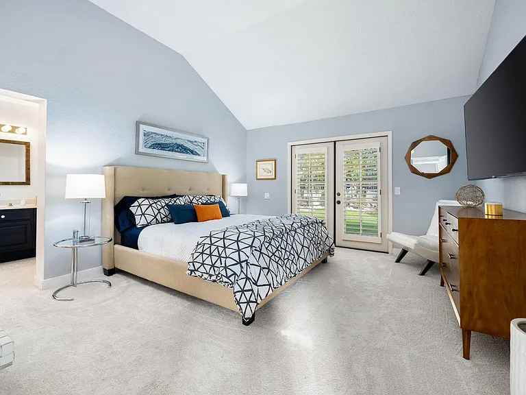 Primary bedroom with smart TV and doors leading to backyard.