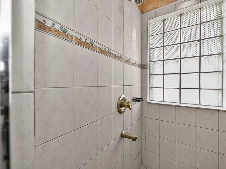 Tiled shower surround with built-in soap dish and a glass-block window for privacy while letting in natural light.