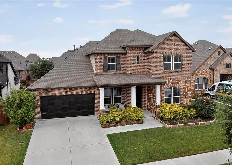 French provincial home featuring a shingled roof, a garage, concrete driveway, a porch, and brick siding
