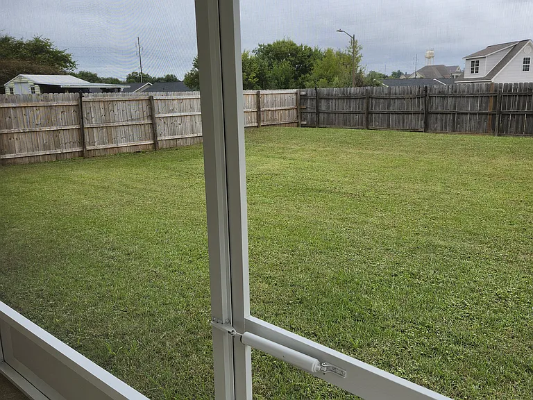 Backyard view from the screened covered porch; fully fenced backyard; very spacious; well manicured.