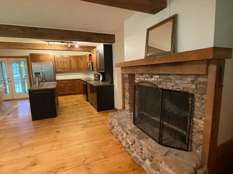Wood-burning fireplace with view into kitchen.