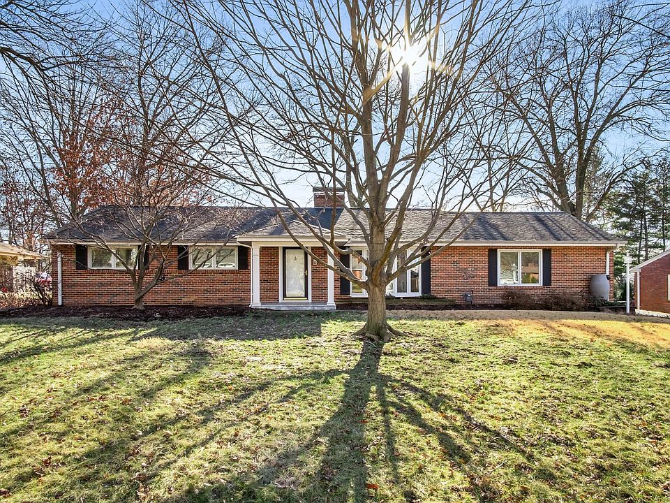 Beautiful front yard with trees, custom landscaping, and raingarden on the side with native perennial flowers.