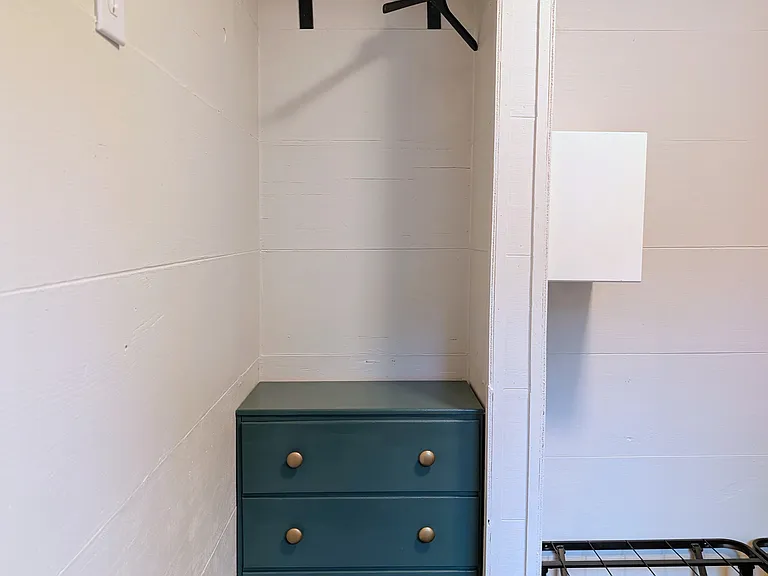 Closet area with four-drawer clothes dresser and clothes bar