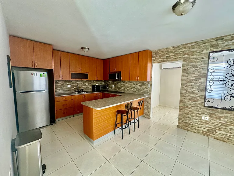Kitchen equipped with stove, refrigerator, coffee maker and portable oven.