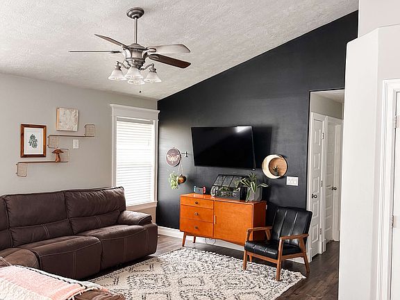 This stylish living room features a bold black feature wall that adds a striking focal point to the space. It opens to the kitchen and dining area, creating a spacious, airy feel perfect for entertaining or relaxing.