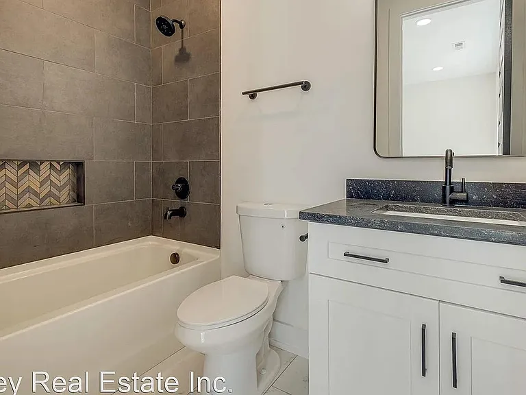 Updated full bath with tiled tub/shower surround, built-in niche, and wide vanity with countertop sink and storage.