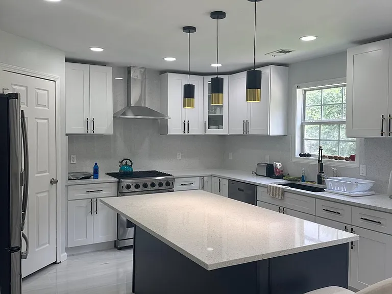 Updated kitchen with large island, ample white cabinetry, stainless steel appliances, and pendant lighting by the sink window