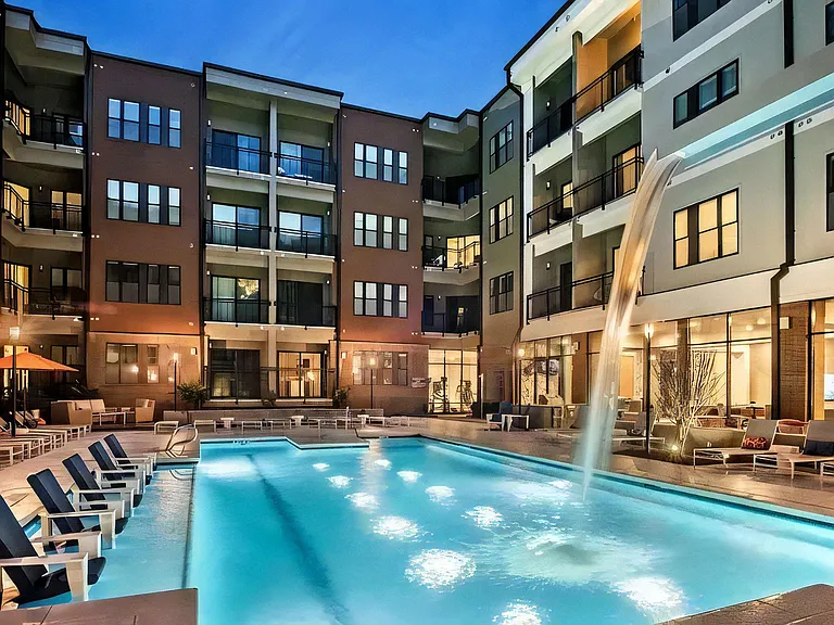 Luxurious Community Pool Surrounded by Seating Areas and Lit for Nighttime Ambiance