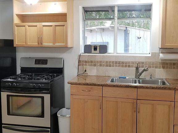 Kitchen with bay window, granite counters, refrigerator & oven/stove.