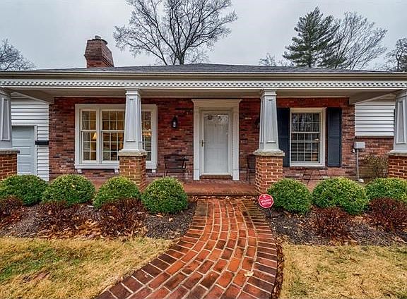 Charming covered front porch with brick sidewalk and distinctive columns greets guests