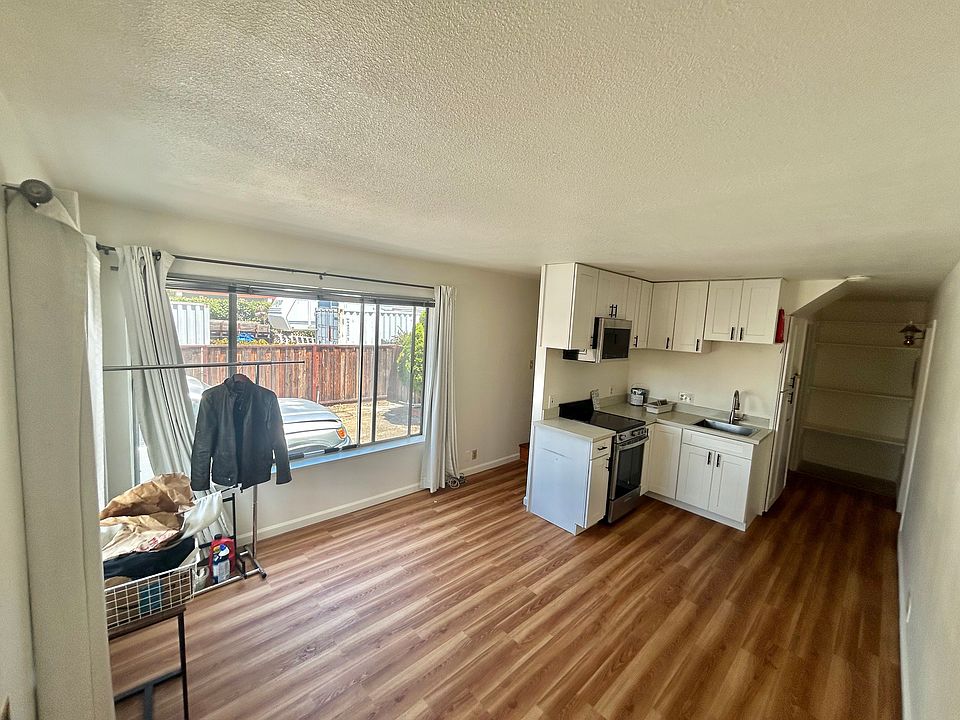 Main living room with view of kitchen and hallways. Left hallway leads upstairs, right hallway leads to 2nd bedroom, bathroom/laundry room, and large pantry.