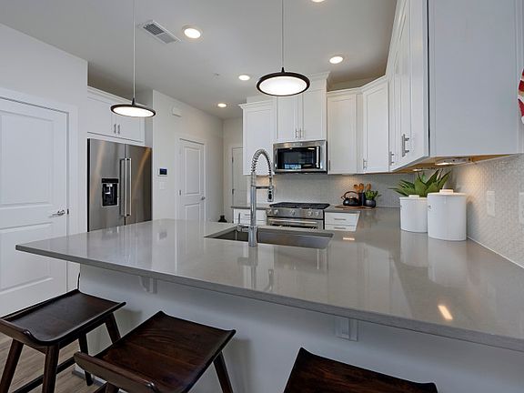 Kitchen with Fossil Gray Quartz Countertops in the New Lawrence Condo for Sale at Crown by Pulte Hom