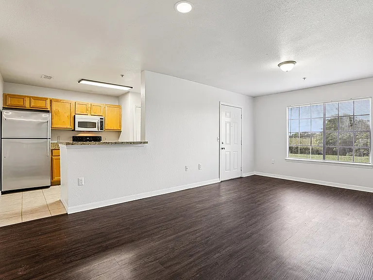 Contemporary apartment with open-concept living area featuring sleek hardwood floors and a modern kitchen with stainless steel appliances.
