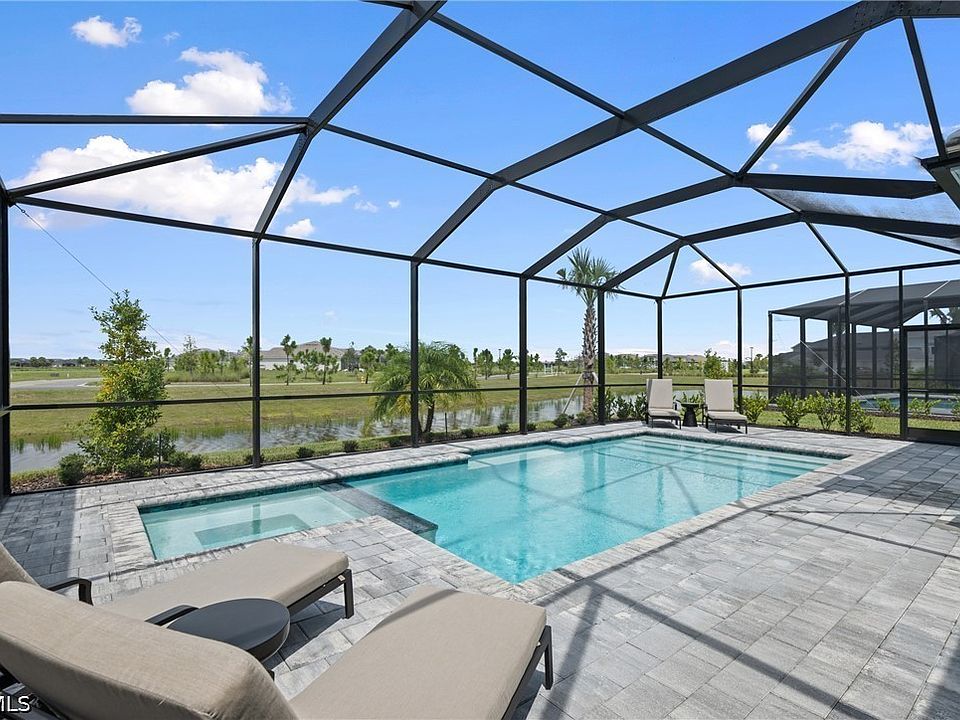 Heated saltwater pool and spa under a screen enclosure with a pond and golf course beyond, Webb’s Reserve, Punta Gorda, Florida