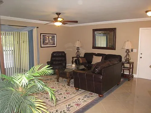 View from hallway of living room with matching brown leather loveseat, sofa and recliner