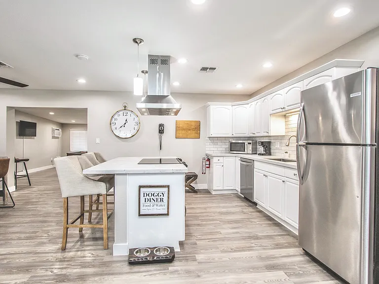 Beautiful, modern kitchen at Casa Del Sol, Tempe rental home. White shaker cabinets, quartz counters, stainless steel appliances, breakfast bar with seating, & dog-friendly details for a stylish, functional space in a prime Tempe, AZ location.
