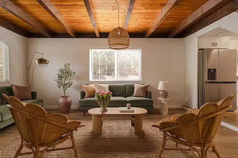 Bright and welcoming living room with comfy sofas, stylish rattan chairs, and a wooden coffee table stocked with board games. Perfect mood for game nights, cozy Netflix binges, or lounging on an air mattress.