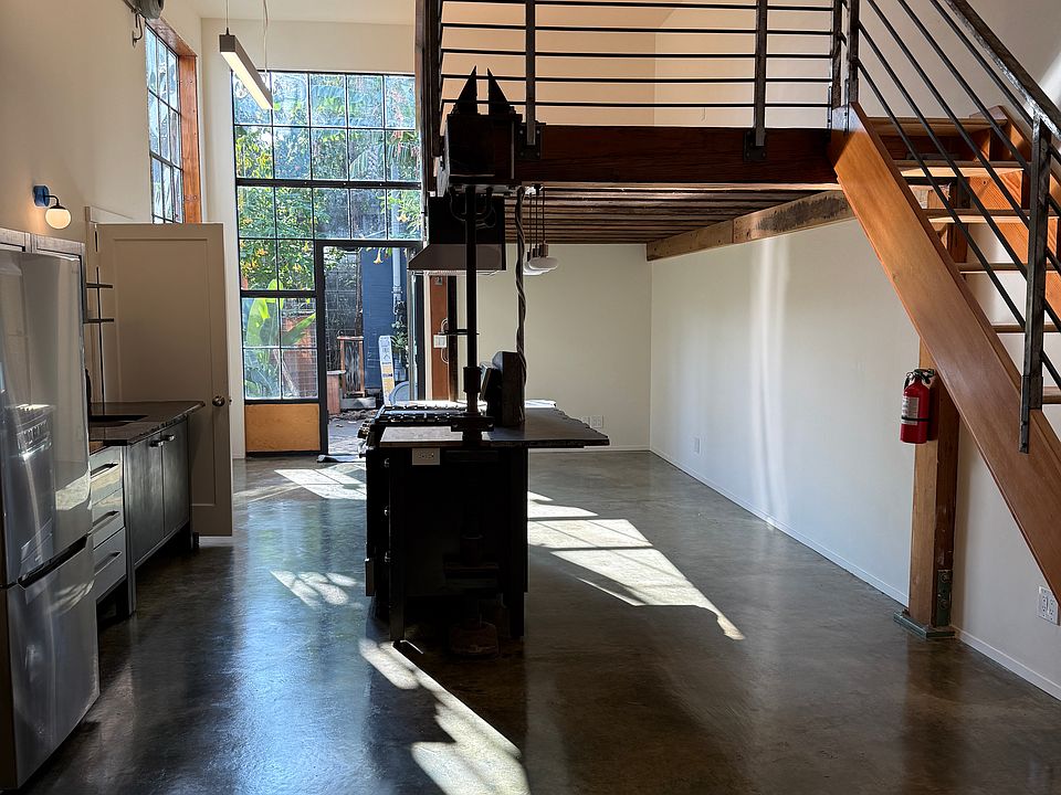 LOOKING FROM THE BACK OF UNIT. STAIRS TO LOFT ON RIGHT, KITCHEN ON THE LEFT, ENTRY DOOR/WINDOW IN THE DISTANCE