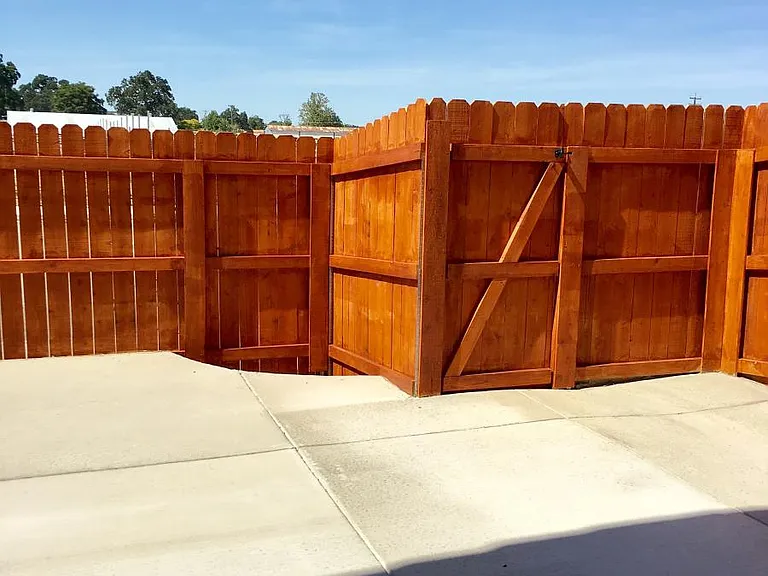 Fenced concrete patio has been updated, with stained concrete and plants.