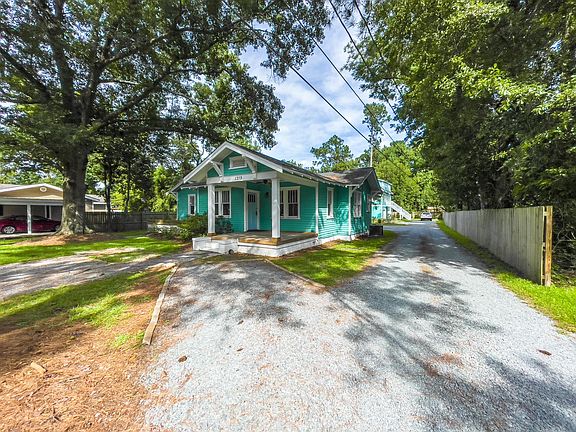 Front of home showing 2 gravel parking spaces, and driveway to access another 4 gravel parking spaces for the front house.