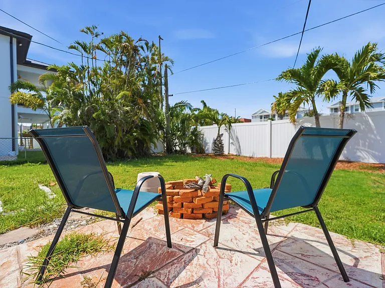 Fenced backyard includes patio off kitchen with gas grill, table/chairs and fire pit.