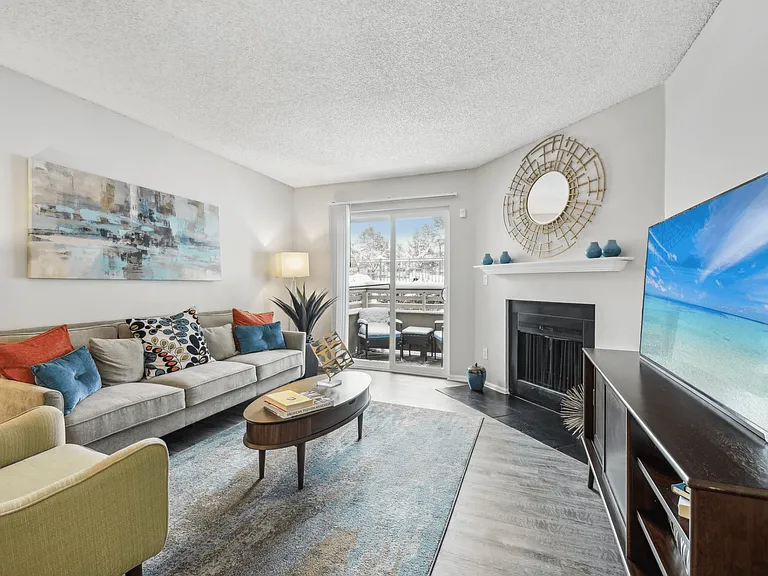 Open living area with wood-style floors, a breakfast bar, and private balcony access.