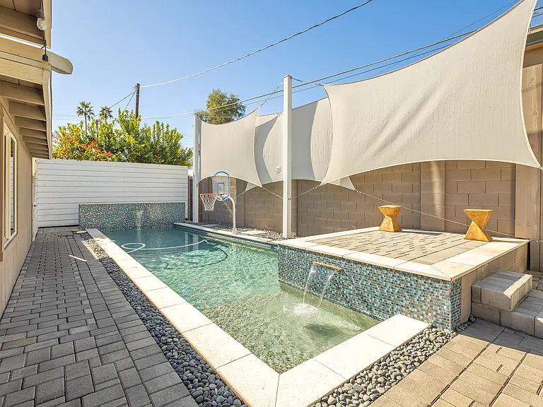 Private swimming pool with dual cascading waterfalls and dedicated sun deck for sunbathing.