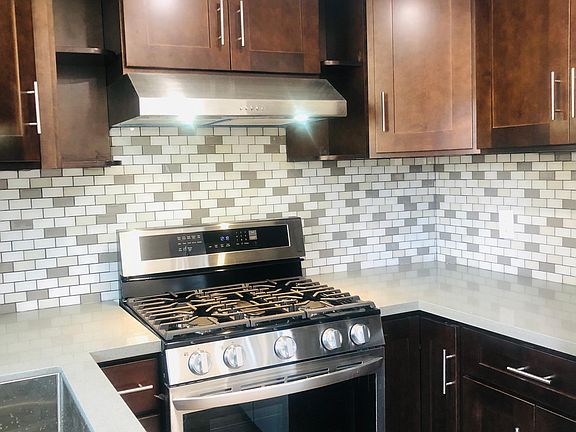 New kitchen cabinets with stainless steel hood, sink, and stove
