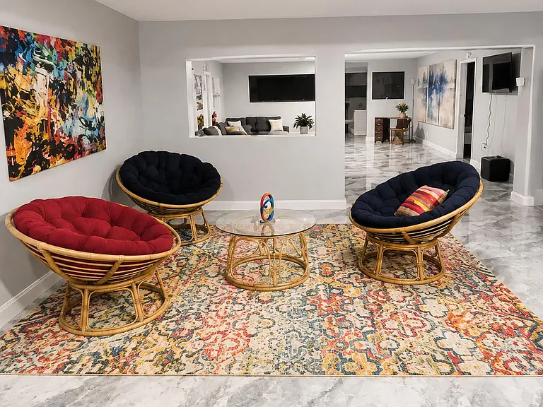 Spacious lounge area with tiled floors, a large area rug, and comfortable seating arranged around a coffee table.