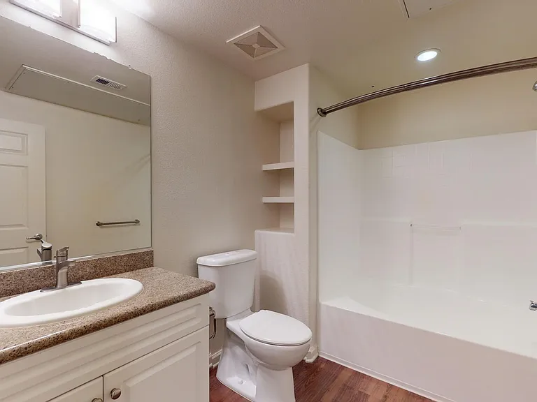 Apartment bathroom with wood-style flooring.
