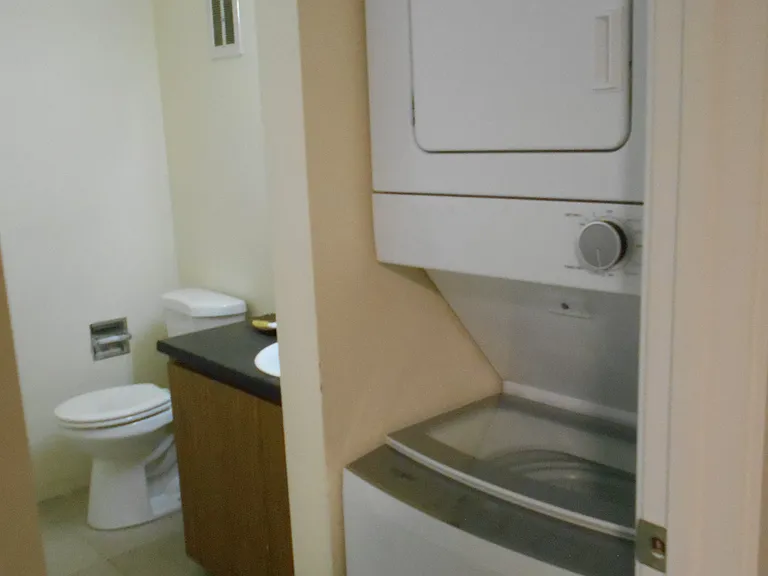 There is a laundry / half bath combo between the living room and kitchen. Has a stack washer & dryer, toilet, and sink.