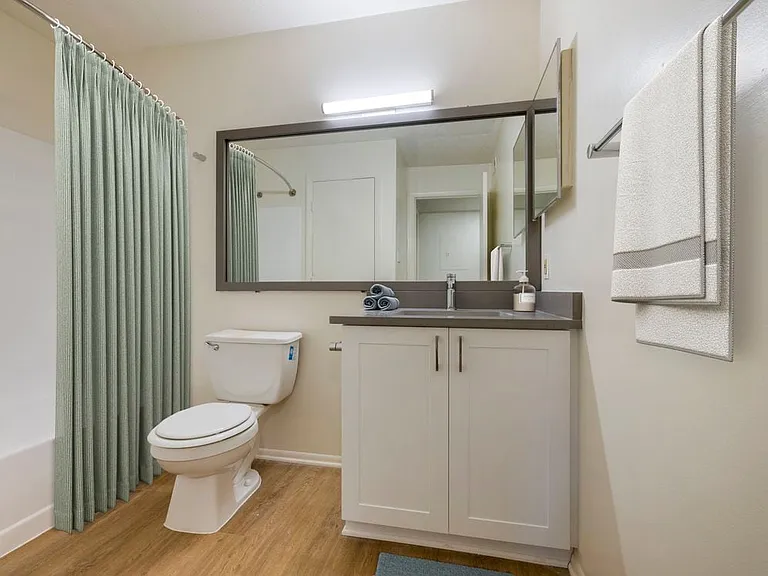 Renovated Meadows II bath with white cabinetry, grey quartz countertops. and hard surface flooring