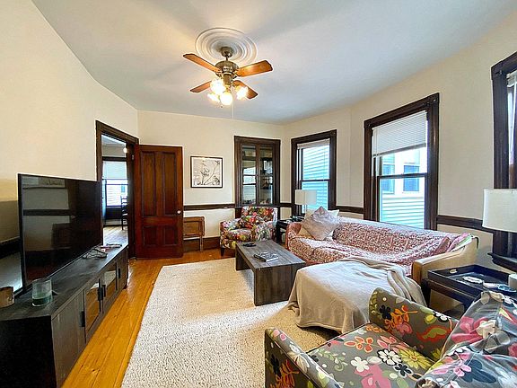 Living room. Large couch with 2 chairs. Built in glass storage/bar area