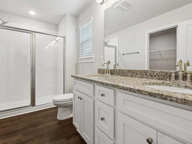 Primary bathroom featuring a double vanity and walk-in shower.