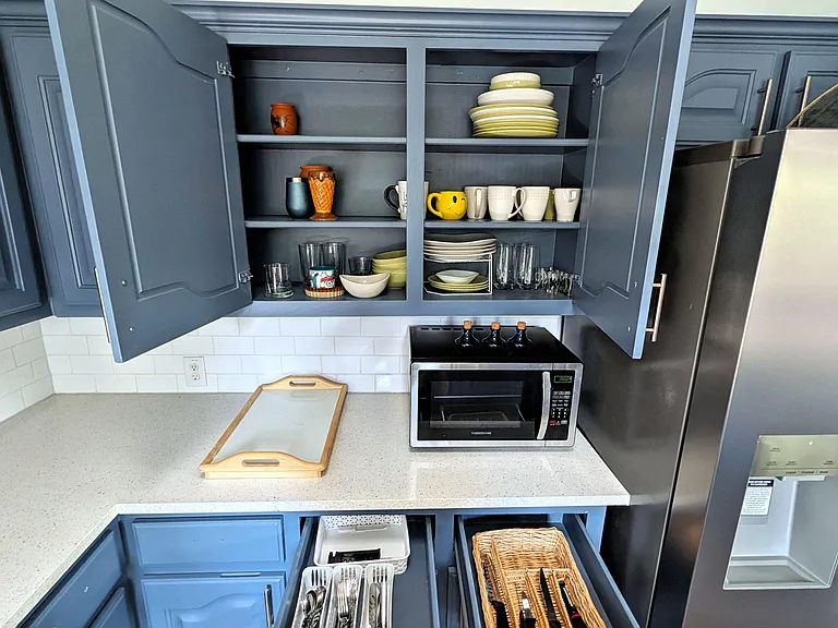 Well-equipped kitchen with ample cabinet storage, generous counter space, and stainless-steel refrigerator plus microwave.