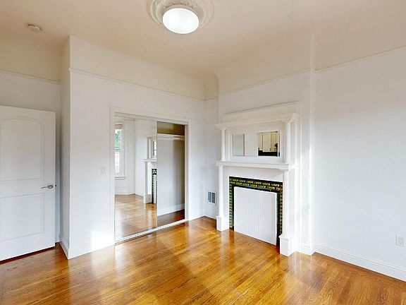 Living area with a wood-like flooring, closet with mirror, and a fireplace