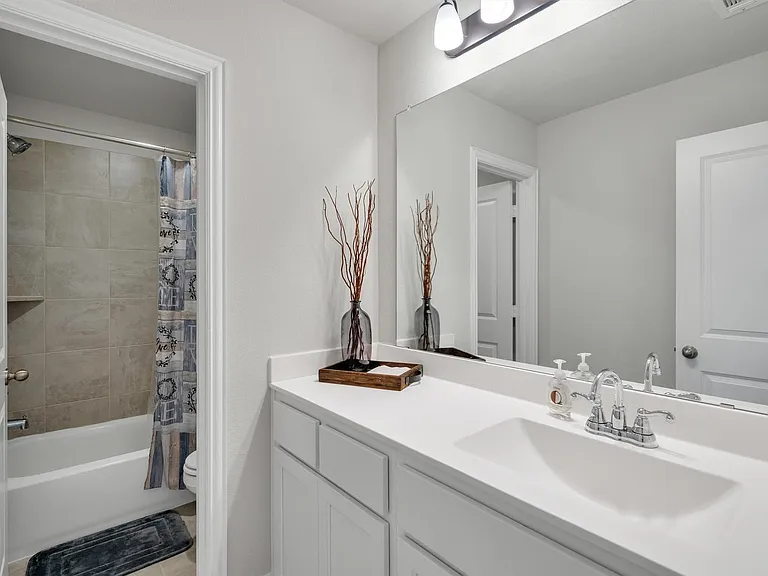 Bathroom featuring a white vanity with an integrated sink, polished chrome faucet, a large rectangular mirror, and a three-light vanity fixture