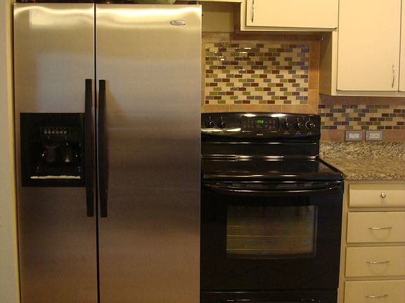 Kitchen w/Granite Counters, Glass Tile, and Stainless/Black Appliances