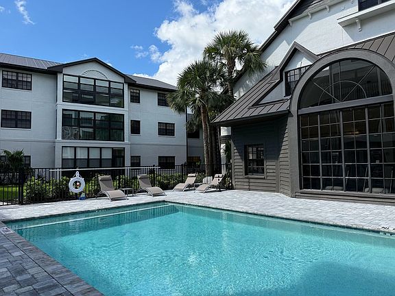 Inviting apartment complex with a refreshing pool, surrounded by lush greenery and stylish architecture, perfect for relaxation and leisure.