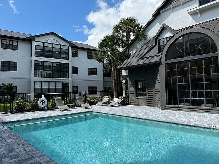 Inviting apartment complex with a refreshing pool, surrounded by lush greenery and stylish architecture, perfect for relaxation and leisure.
