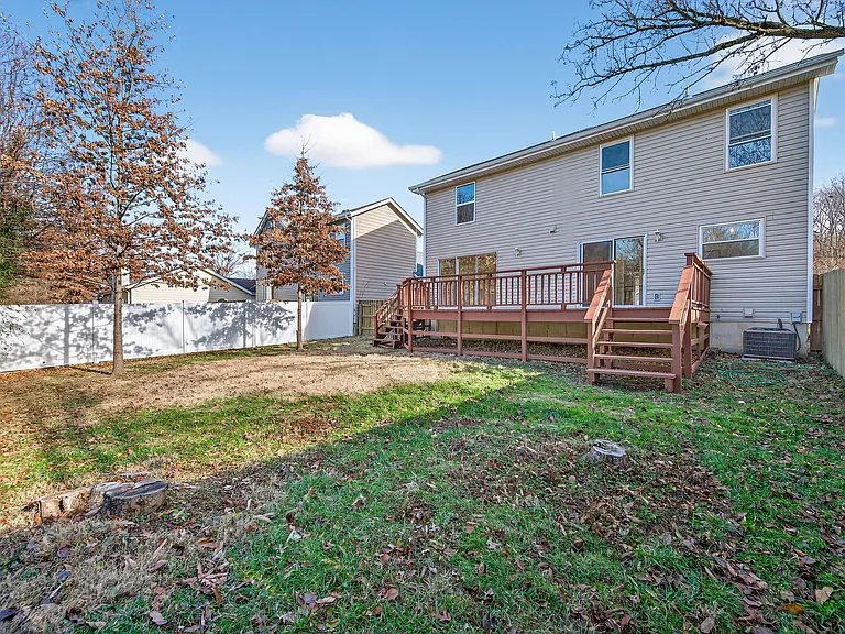 Rear view of house featuring a fenced backyard, a deck, and stairs