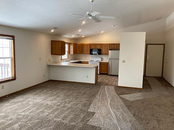 View of other part of great room showing window at balcony, open kitchen, and entrance to apartment.